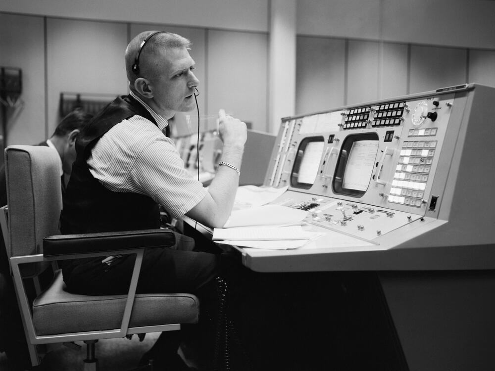 Black and white photo, man sitting at console