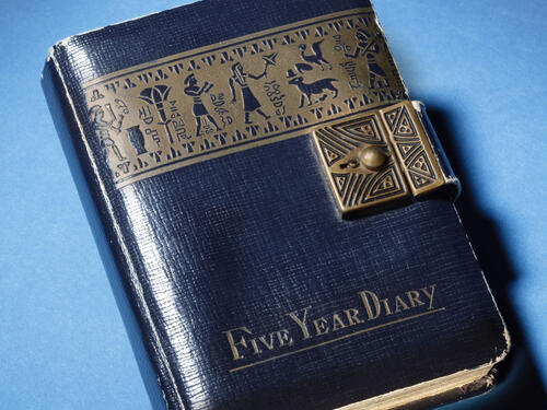 Blue-colored leather diary cover with golden-colored decal of Egyptian characters.