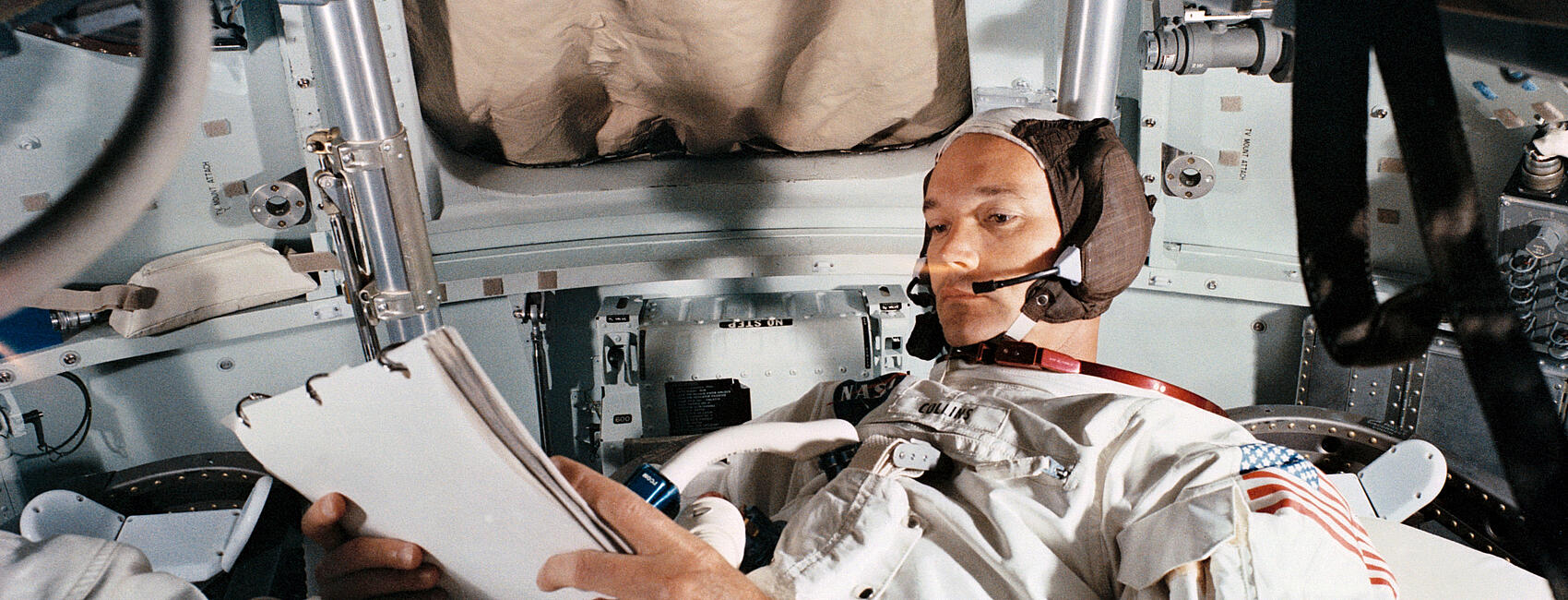 A man in a spacesuit reclines inside space capsule.